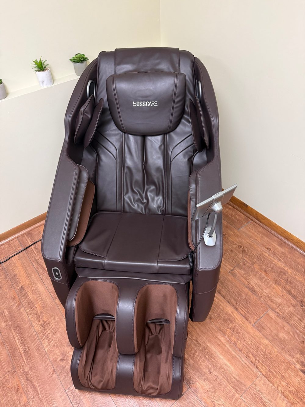 The Sozo zero gravity massage chair, a dark brown reclining chair with small plants on the shelf beside it